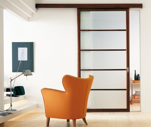 Modern interior sliding door featuring acid etched laminated glass with canaletto walnut framed sliding panel